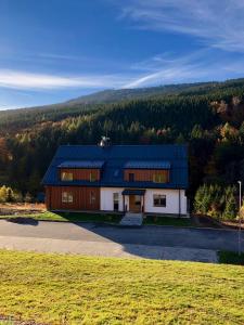 a house with a blue roof on top of a field at Apartmán Pod Mamutem in Dolní Morava