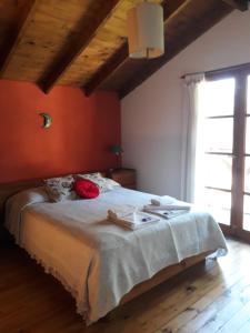 1 dormitorio con 1 cama grande y pared de color naranja en Cabañas "Lola Mora" en Tandil