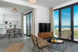 a living room with a television and chairs and tables at Hillside Villa - Thea in Limenas