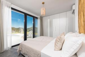 a bedroom with a white bed and a large window at Hillside Villa - Thea in Limenas +37 photos