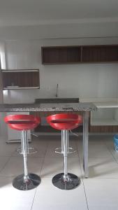 a kitchen with two red bar stools in front of a counter at Lacqua Diroma Caldas Novas PB Turismo in Caldas Novas