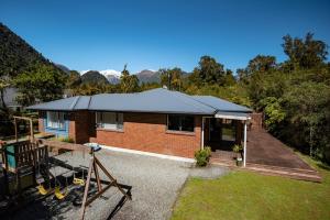 a small brick house with a roof at Six Kamahi Guest House & Studio Unit in Franz Josef