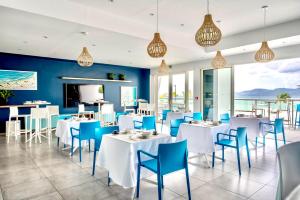 um restaurante com mesas brancas e cadeiras azuis em Résidence Hôtelière Poséidon Caraïbes em Fort-de-France