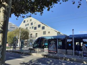 a train on a city street with a building at Une chambre à l'Economat in Bordeaux