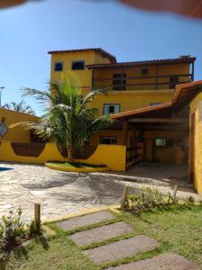 a yellow building with a surfboard in front of it at Casarão Familiar Eixo Cabo Frio Buzios com piscinão in Cabo Frio