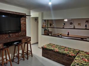 a living room with a flat screen tv and a bench at Casarão Familiar Eixo Cabo Frio Buzios com piscinão in Cabo Frio