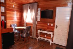 a room with a table and a tv and a window at Chalés Poncho Serrano in Gramado