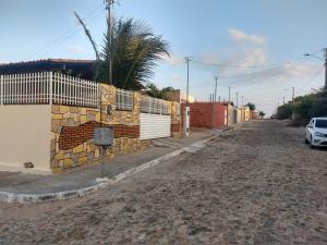 an empty street with a fence and a palm tree at Sua casa no litoral in Parnaíba