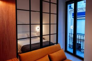 een kamer met een bed, een bank en een raam bij Apartamentos Plaza de España 6 in Villanueva de la Serena