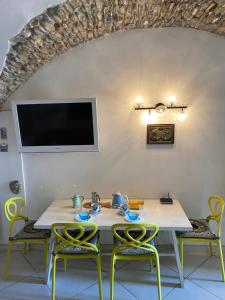 una sala da pranzo con tavolo, sedie e TV di Frantoio a Riva Ligure