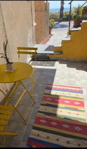 un tavolo giallo e una sedia su un marciapiede con un tappeto di Frantoio a Riva Ligure