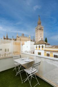 a table and chairs on a balcony with a clock tower at Historic Building Cathedral in Seville