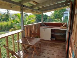 une terrasse en bois avec une table et une cuisine dans l'établissement Kiki's Nature Cabin, à Calibishie