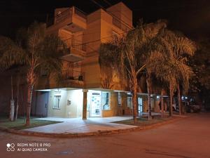 um edifício à noite com palmeiras em frente em El Descanso Hotel em Termas de Rio Hondo