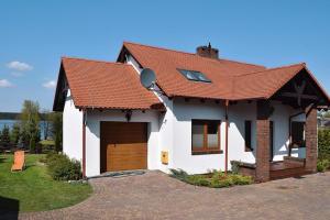 ein weißes Haus mit einem roten Dach und einer Auffahrt in der Unterkunft holiday home at the lake in Kiedrowice in Kiedrowice