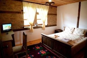 a bedroom with a bed and a television and a window at Guest House Pri Malkiya in Leshten