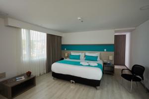 a hotel room with a large bed and a chair at Hotel Nivari Duitama in Duitama