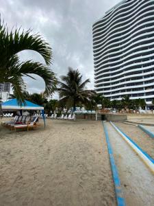 a beach with chairs and palm trees and a building at Departamento frente al mar, FONTAINE BLEAU in Tonsupa