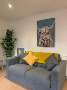 a couch in a living room with a painting of a cow at The Coach House in Salisbury