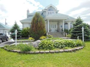 uma casa branca com um jardim em frente em Gite Du Lac St-Prime em Saint-Prime