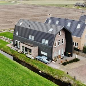 una grande casa con una macchina parcheggiata di fronte di Oomes Huus - Sleep by Hästens, Wake with Coffee a Den Hoorn