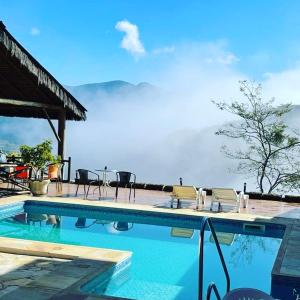 a swimming pool with chairs and a view of the ocean at Pousada R.N.C. Nosso Paraíso in Teresópolis
