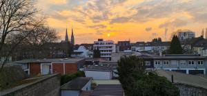 een uitzicht op een stad met een zonsondergang op de achtergrond bij ELENA flat NELKE Oberhausen Zentrum CentrO Westfield in Oberhausen