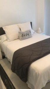 a white bed with a love pillow on it at Los Colimbos in Torremolinos