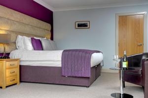 a bedroom with a king sized bed with purple accents at Philipburn Hotel, BW Signature Collection in Selkirk