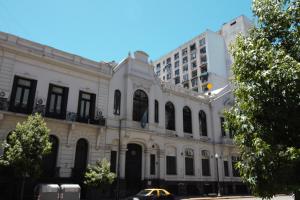 Un edificio blanco con un coche aparcado delante. en PORTEñO CENTRAL apart GALERIAS PACIFICO, en Buenos Aires