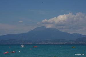 a group of boats in the water with mountains in the background at Camping Wien in Peschiera del Garda