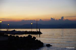 a sunset over a body of water with lights at Camping Wien in Peschiera del Garda