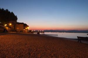 a bench on a beach next to a body of water at Camping Wien in Peschiera del Garda