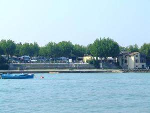 a blue boat in the water near a beach at Camping Wien in Peschiera del Garda