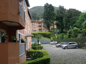 um parque de estacionamento com carros estacionados em frente a um edifício em Apartamento Vivendas do Eucalipto em Petrópolis