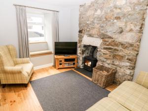 sala de estar con chimenea de piedra y TV en Haddef en Nefyn