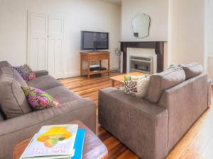 a living room with two couches and a tv at Youngs Cottage in Port Fairy