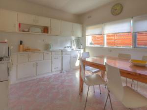 Una cocina con una mesa de madera y gabinetes blancos. en Youngs Cottage, en Port Fairy