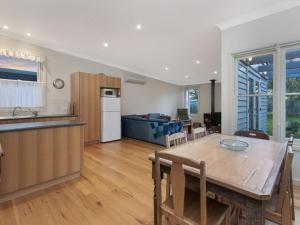 uma cozinha e sala de jantar com uma mesa de madeira e uma cozinha e uma sala de estar em Plovers Rest em Port Fairy