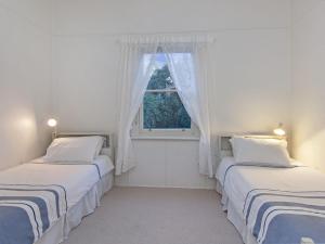 two beds in a room with a window at Plovers Rest in Port Fairy