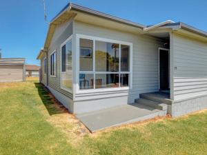 a small house with a porch and a lawn at Wings and Waves in Port Fairy