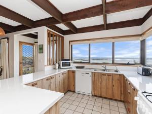 a kitchen with wooden cabinets and white appliances and windows at Swimmers Rest 1 Bedroom in Port Fairy