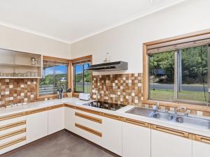 a kitchen with white cabinets and a sink and windows at Kepal House in Port Fairy