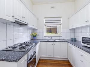 a white kitchen with a stove and a sink at Fairholme Apartment in Warrnambool