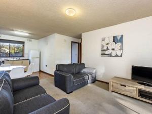 a living room with a couch and a tv and a table at Eastern Beach Unit 3 in Port Fairy