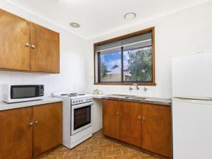 - une cuisine avec des placards en bois et un réfrigérateur blanc dans l'établissement Eastern Beach Unit 6, à Port Fairy