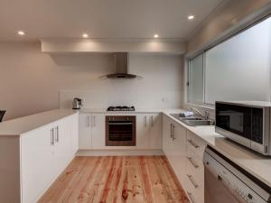 a kitchen with white cabinets and a wooden floor at Malseeds in Port Fairy