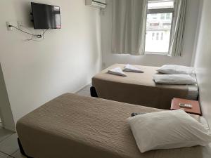 a hotel room with two beds and a television at Hotel San Carlos in Balneário Camboriú +18 photos