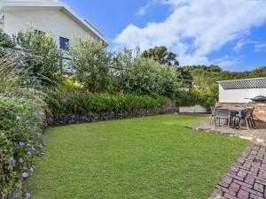 un jardín con mesa, sillas y pared de piedra en East Beach Retreat, en Port Fairy