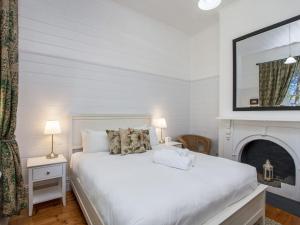 a white bedroom with a white bed and a fireplace at Eamont On Sackville in Port Fairy